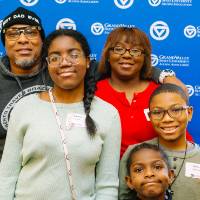 A family poses for a group photo in front of the GVSU backdrop